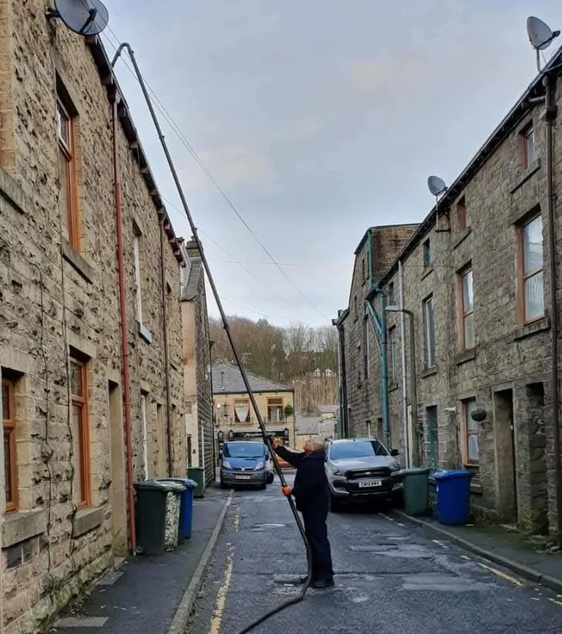 Paul, owner of PW Gutter Cleans, cleaning gutters with a pole system in Haslingden